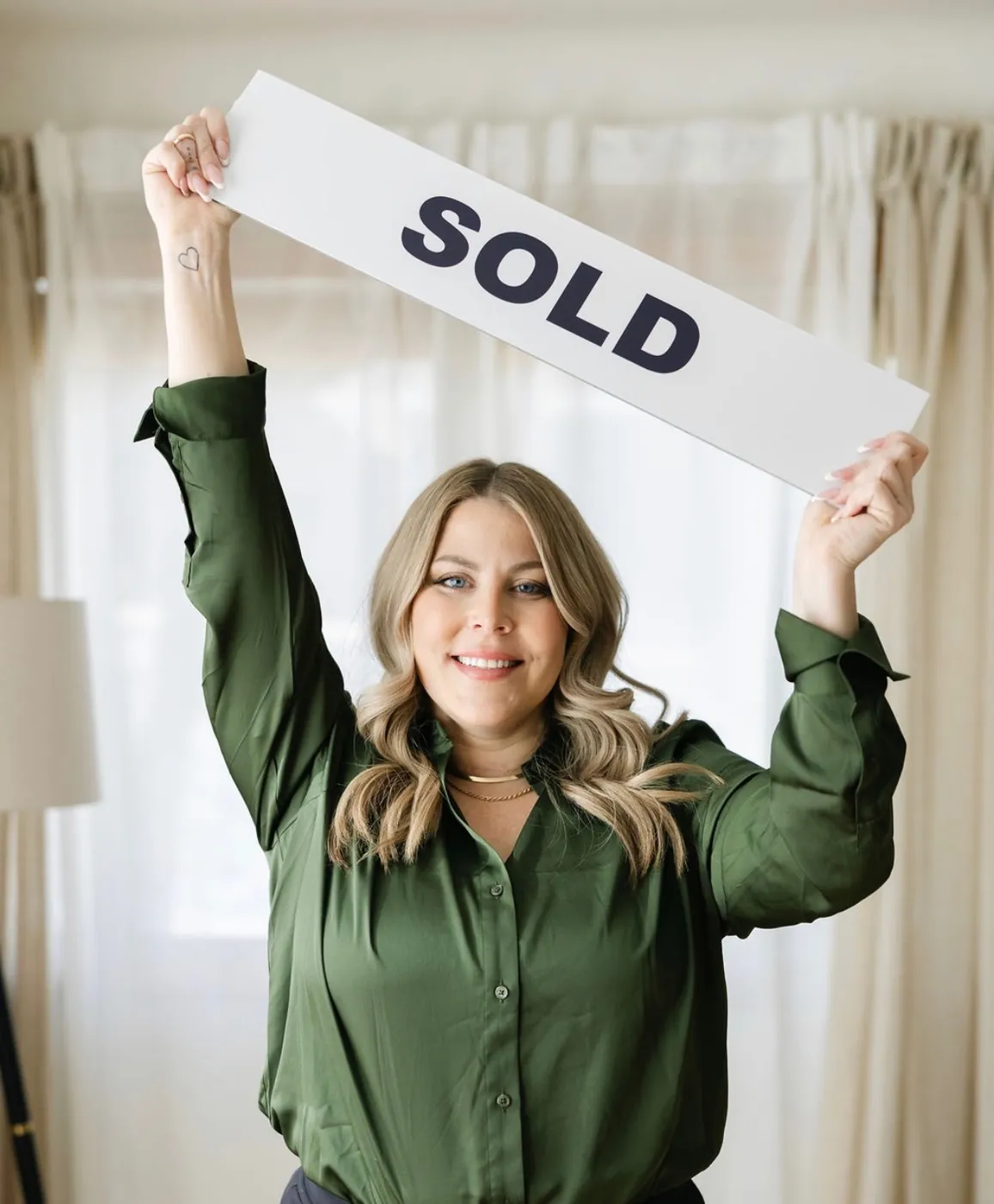 Shelby Pavlovic holding a SOLD sign, Medicine Hat REAL Broker Realtor